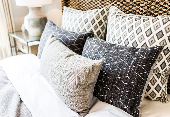 Closeup-of-new-bed-comforter-with-decorative-pillows,-headboard-in-bedroom-in-staging-model-home,-house-or-apartment